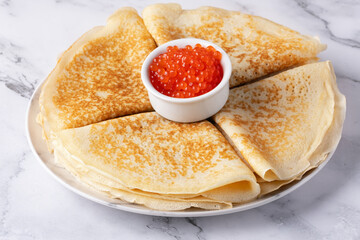 Pancakes with red caviar on a marble table