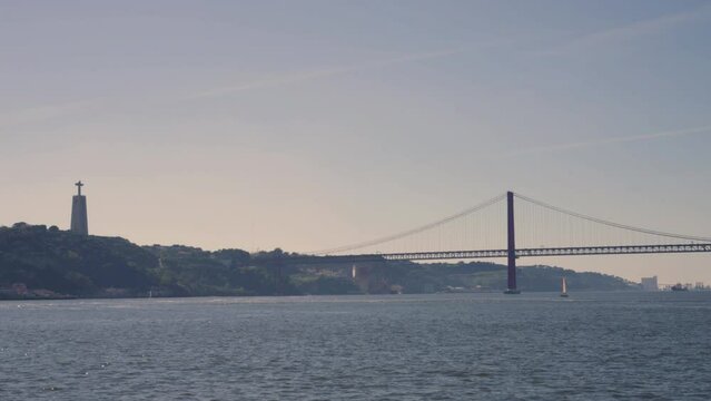 POV shot from from boat on Tagus River in Lisbon, Portugal, with view of Christ the Redeemer statue in Almada, Cacilhas