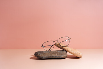 Vision glasses with black frames on stones against a pink background.