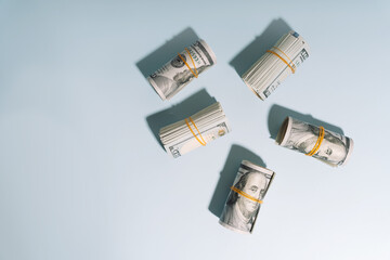 Tubes of hundred dollar bills rewound with an elastic band on a light background. High quality photo