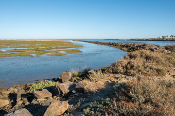 Breakwater of large stones next to the marshes on the coast of Huelva, Spain.