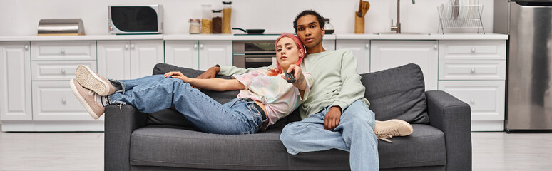appealing interracial couple in homewear spending time together and watching movies at home, banner