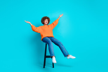 Full length portrait of overjoyed positive person sit chair raise arms look empty space isolated on turquoise color background
