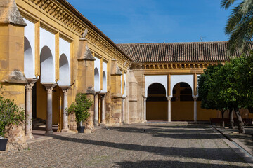 Surrounding buildings of the Mosque–Cathedral of Cordoba, Andalusia, Spain seen from the patio de los naranjos (orange trees) against a clear blue sky