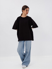 mockup of a black loose-fitting t-shirt on a young beautiful girl