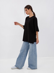 mockup of a black loose-fitting t-shirt on a young beautiful girl