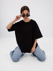 mockup of a black loose-fitting t-shirt on a young beautiful girl