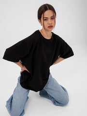 mockup of a black loose-fitting t-shirt on a young beautiful girl