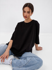 mockup of a black loose-fitting t-shirt on a young beautiful girl