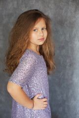 a brown-haired girl with curly hair in a shiny pink festive dress with sequins