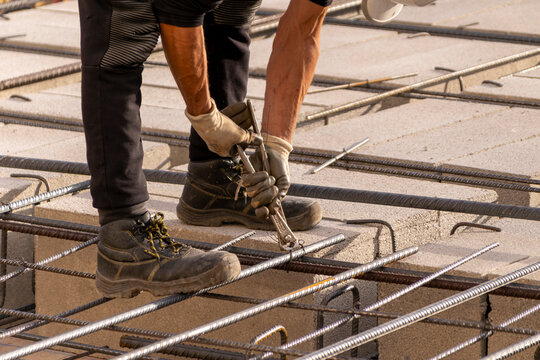 Obrero de la construcción atando las barras de acero corrugado en un estructura de hormigón armado