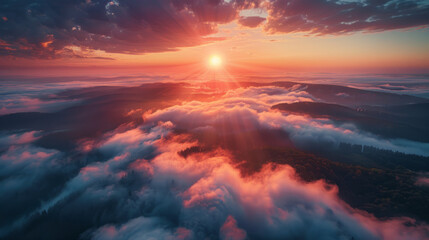 A breathtaking aerial view of a misty mountain landscape bathed in the warm glow of a rising sun. The sunlight pierces through the clouds, casting rays and illuminating the undulating hills below.