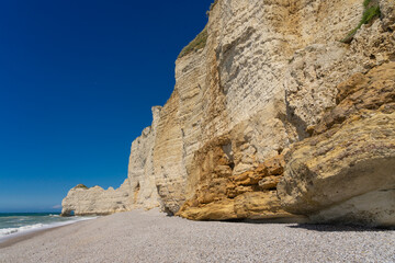 Fototapeta premium Etretat cliffs and beach in the Normandie region of France in a sunny day. Falaise d'amont chalk clliffs in the Alabaster coast.