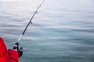 Fisherman holding a fishing rod on the background of the sea