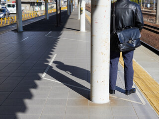 冬の朝の通勤時間の駅で電車待ちの男性の姿