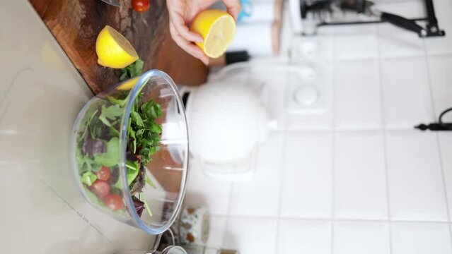 Closeup of female hands pouring oil in vegetable salad, cooking dietary meal from fresh vegetables in bowl. Healthy food salad at home in white design kitchen. healthy eating concept. 