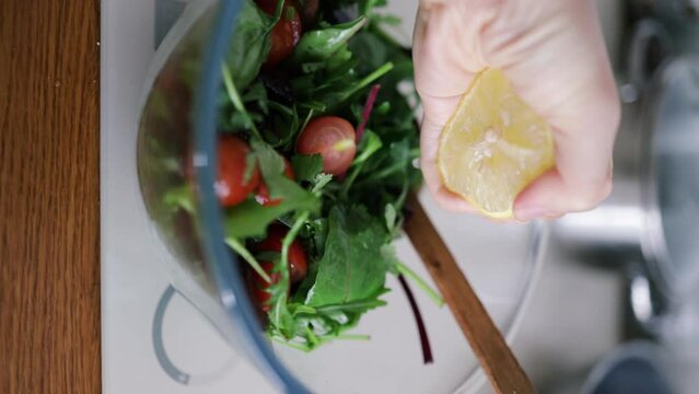 Closeup of female hands pouring oil in vegetable salad, cooking dietary meal from fresh vegetables in bowl. Healthy food salad at home in white design kitchen. healthy eating concept. 