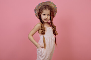 Little girl with pigtails wearing hat on pink background