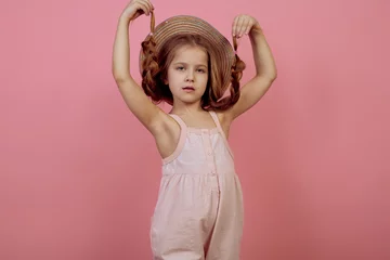 Fotobehang Little girl with pigtails wearing hat on pink background © Ирина Щукина