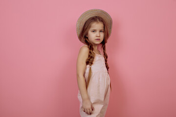 Little girl with pigtails wearing hat on pink background