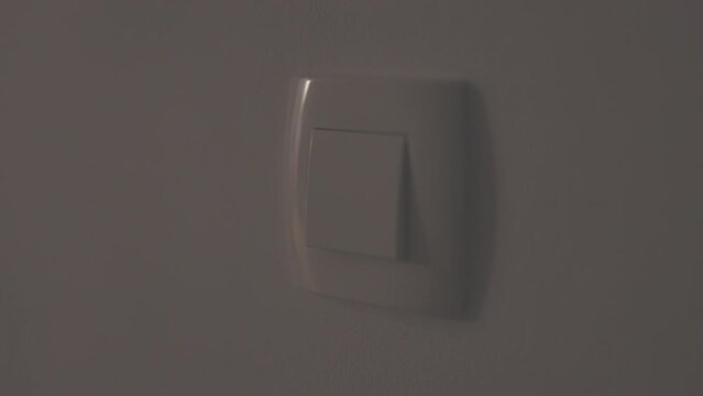 Close up shot of a woman hand turn light switch on.