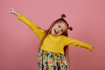 Little smiling girl with hands up on pink background