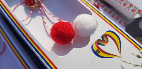 A pair of tiny pom poms- balls - red and white - a symbol of Spring - on a light background with a...