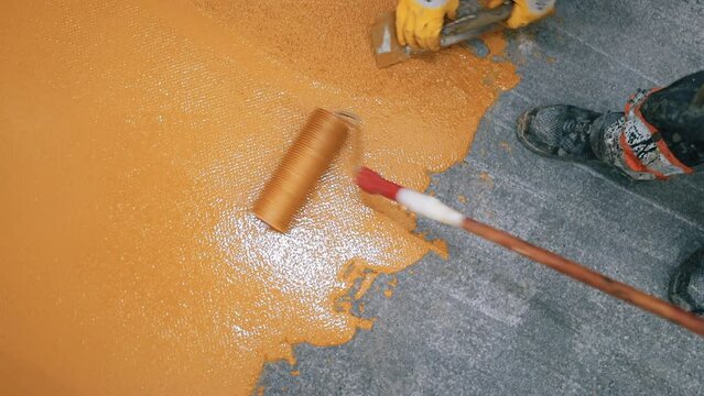 Self-Leveling Floors on a large industrial hall, A worker pours and apply the resin.