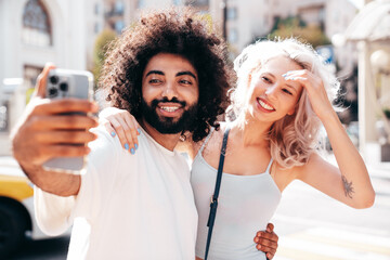 Smiling beautiful woman and her handsome boyfriend. Woman in casual summer jeans clothes. Happy cheerful family. Female having fun. Sexy couple posing in the street at sunny day. Take selfie