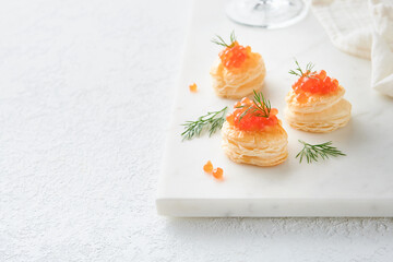 Salmon red caviar toast. Christmas canape or toast with red caviar on white plate on light background. Idea to xmas snack. Gourmet food. Texture of caviar. Seafood.