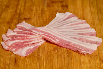 slices of bacon on a wooden board.