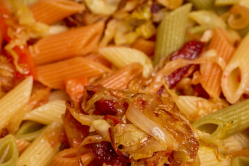 pasta with vegetables in a pan while they are cooked on the stove.
