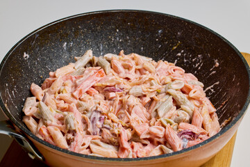 pasta with vegetables in a pan while they are cooked on the stove.