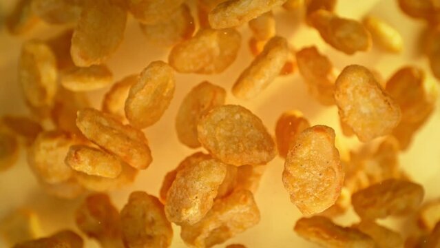 Super Slow Motion Shot of Flying Chicken Nuggets Towards Camera on Golden Background at 1000fps.