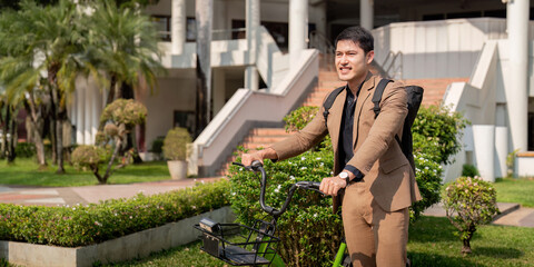 Asian businessman in a suit is riding a bicycle on the city streets for his morning commute to work. Eco transportation concept, sustainable lifestyle concept