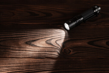 Flashlight and a beam of light in darkness. A modern led lamp with bright projection on dark wood...
