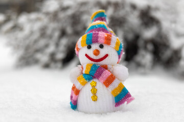 A fabric snowman in hat, scarf, in winter forest. Concept of winter, snow and childhood.
