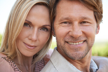 Portrait, hug and couple in a garden with love, support and bonding outdoor together. Care, face and mature people embrace in a park for travel, vacation and free time on the weekend or holiday