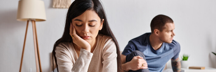Obraz premium young depressed multiethnic couple sitting in bedroom at home, family misunderstanding concept
