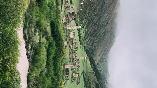 View of the medieval Targim tower complex in the Caucasus mountains surrounded by greenery. The Caucasus Mountains on a cloudy day in Ingushetia. Russia, 4K.