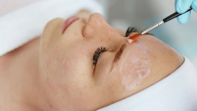 Beautician cosmetologist applies cosmetic product gel bubble acid peeling mask on face. Skincare and cosmetology spa concept.