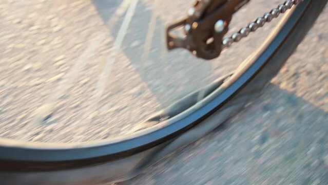 A man rolls a bicycle with a punctured rear wheel along an asphalt road. A broken tube in a wheel tire. Slow motion, close-up