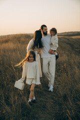 Stylish family in the park in the evening light. Lights of the sun. Mom, dad and child are happy...