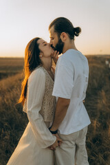 a kiss between a man and a woman who are walking in the evening in nature. The man touches the woman's face with his hand and leans a little towards her