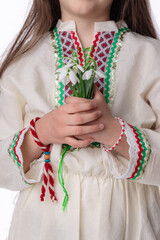 Bulgarian girl in ethnic costume with bouquet of snowdrops and a red and white symbol of the holiday of the spring martenitsa Baba Marta day, Bulgaria - 748733256