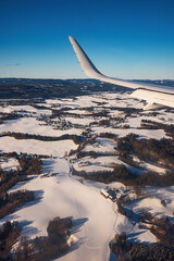 Airplane flying low over snowy mountains hills and preparing for landing to the airport, view from plane window of wing turbine and skyline - 748734051