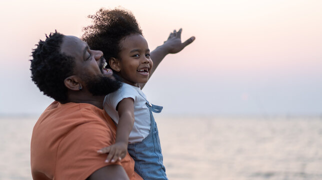 African love family father and daughter enjoying a carefree moment  strength and happiness as he lifts his young daughter, childhood, joy, leisure, parenting and outdoor activities, Father day