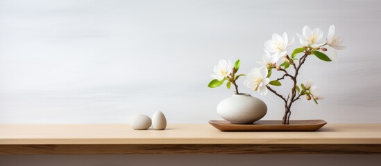 A vintage wooden table shelf is adorned with a vase containing white flowers, accompanied by three rocks. The scene exudes a minimalist and zen aesthetic in a modern interior design setting.