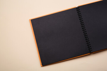 Open photo album on beige background, top view. Space for text