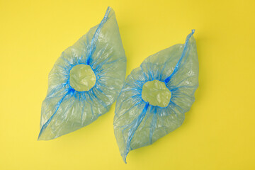Pair of blue medical shoe covers on yellow background, top view